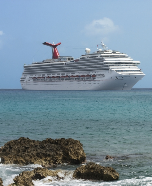 Travel X A large cruise ship with a distinctive red smokestack is anchored in the ocean near a rocky shoreline under a clear blue sky, offering the ultimate Travel X vacation experience. Book Your Trip With Travel X