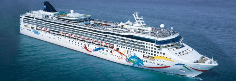 Travel X A large white cruise ship with colorful artwork on its side sails on calm blue waters, offering a floating resort experience. The ship has multiple decks, with passengers enjoying their vacation on the top deck. Book Your Trip With Travel X