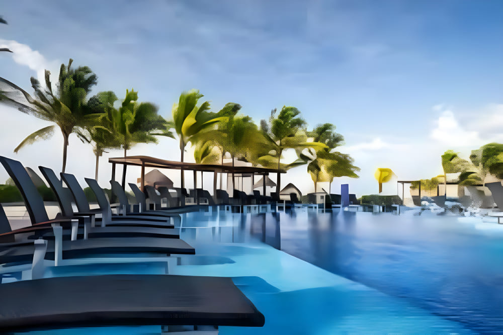 Travel X Outdoor pool surrounded by black lounge chairs under a clear sky with palm trees in the background, perfect for your next vacation. Book your trip to this stunning resort today! Book Your Trip With Travel X