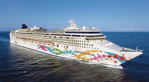 Travel X A large white cruise ship named Norwegian Pearl with colorful decorations on its side sails on the ocean under a clear blue sky, offering a perfect vacation experience. Book your trip now and enjoy this floating resort. Book Your Trip With Travel X