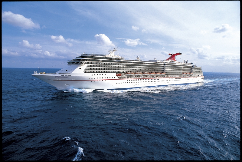 Travel X A large white cruise ship with multiple decks sails on a clear blue ocean under a partly cloudy sky. The name on the side reads "Carnival Legend." Book your trip with Travel X for an unforgettable vacation experience! Book Your Trip With Travel X