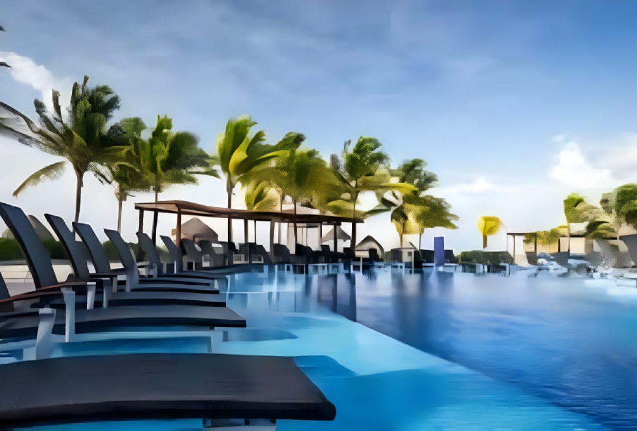 Travel X Outdoor pool surrounded by black lounge chairs under a clear sky with palm trees in the background, perfect for your next vacation. Book your trip to this stunning resort today! Book Your Trip With Travel X